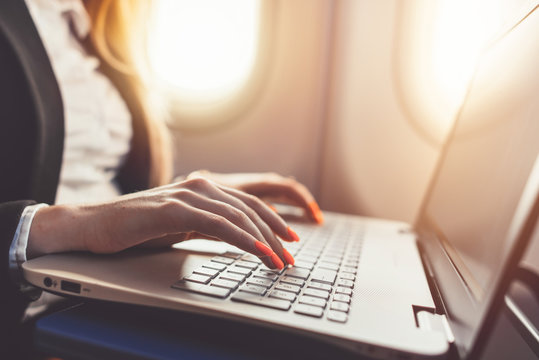 Close-up of female hands using laptop. Woman working while going on business trip by plane