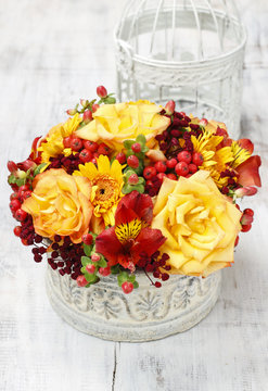 Floral arrangement with orange roses and autumn plants in vintage ceramic vase