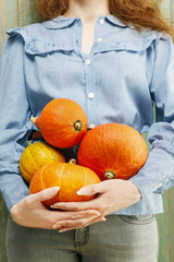 Woman holding orange pumpkins.