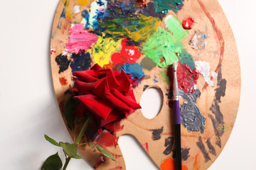 red rose and palette with paints.