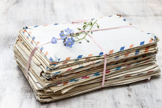 Stack of vintage love letters and forget me not flowers.
