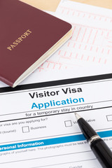 Visa application form with red passport and pen; documents are mock-up