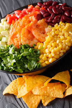 Mexican burrito bowl with shrimp, beans, corn, avocado and herbs closeup. vertical