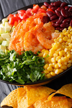 Mexican salad with shrimps, beans, corn, avocado and greens close-up. vertical
