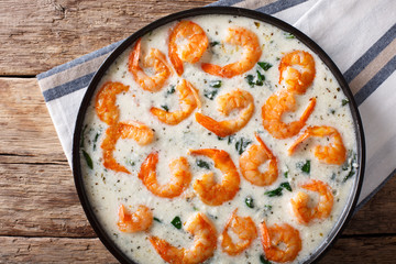 Spicy prawns with spinach in creamy cheese sauce close-up on a plate. horizontal top view