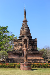 Fototapeta premium Pagoda at Wat Sa Si and walking Buddha statue, Shukhothai Historical Park, Thailand