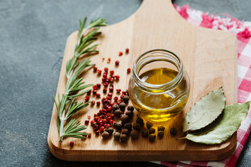 Fresh rosemary, red and black pepper on wooden board top view