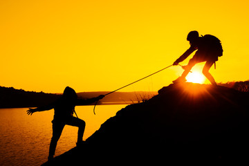 Silhouette women pull the ropes to help each other.
