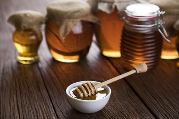 Honey in jar with honey dipper on wooden background 