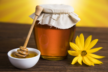 Honey in jar with honey dipper on wooden background 