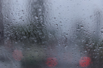 blur image of water car window glass with background of street in raining season