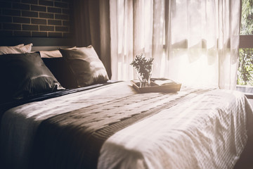 Bed maid-up with clean white pillows and bed sheets in beauty room. Close-up. Lens flair in sunlight.