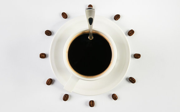 Coffee cup with spoon on saucer and coffee beans