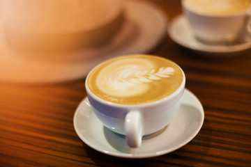 Top view. Two white cups of coffee with black and white smart phones on the wooden table.