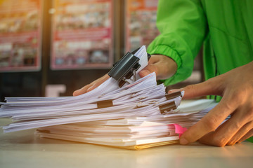 Businessman hands working in Stacks of paper files for searching information on work desk office, business report papers,piles of unfinished documents achieves with clips indoor,Business concept