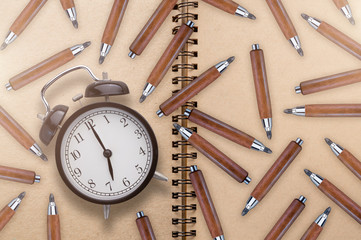 black alarm clock woth wooden handle pencil and free copyspace for our text  with blank page notebook paper