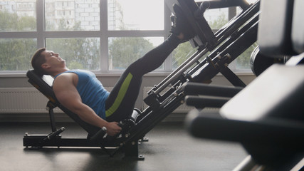 In the gym - muscular man exercising on leg press machine