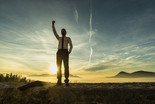 Triumphant Businessman In White Shirt Standing Outdoors With His Fist Raised