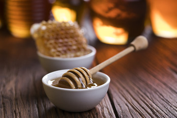 Honey in jar with honey dipper on wooden background 