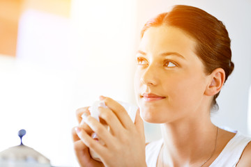 Happy young woman with cup of tea or coffee at home