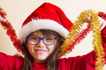 girl with santa hat playing with christmas ribbons