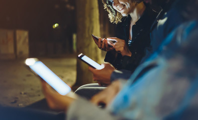 People together pointing finger on screen smartphone on background bokeh light in night atmospheric city, group adult hipsters friends using in hands mobile phone, street online wi-fi internet concept