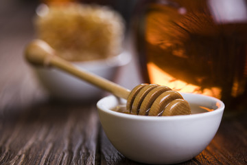 Honey in jar with honey dipper on wooden background 