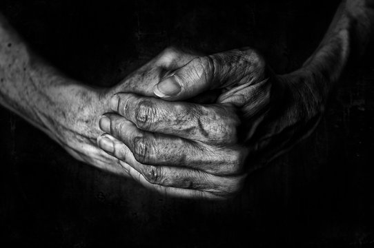 Black and White photo of senior woman hands praying on black background