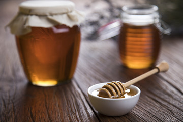 Honey in jar with honey dipper on wooden background 