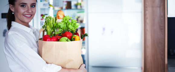 Young woman holding grocery shopping bag with vegetables .Standi