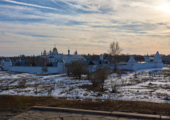 Early spring in Suzdal/In the floodplain of the river there is snow. Here and there the snow melted and last year's grass is visible.An Orthodox monastery is seen in the distance.Golden Ring of Russia