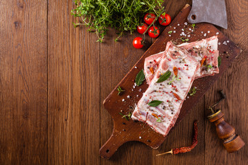 Raw pork ribs, on a plate sprinkled with spices.