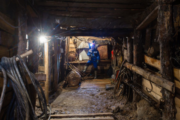 Underground abandoned ore mine shaft tunnel gallery with miner