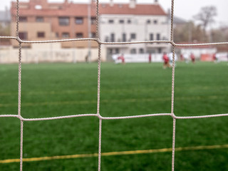 Detalle de una red de fútbol con el campo verde al fondo