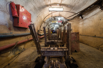 Fototapeta na wymiar Underground emerald ore mine shaft tunnel gallery passage with light and ore cart