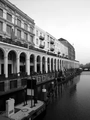 Papier Peint photo autocollant Canal Einfahrt in die Rathausschleuse am Alsterfleet mit den Alsterarkaden im Hintergrund bei grauem Regenwetter in der Hansestadt Hamburg, fotografiert in neorealistischem Schwarzweiß