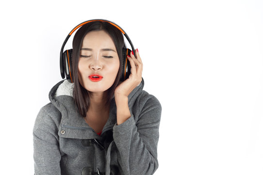 Beautiful asian girl from Thailand listen music from Headphones and sing song on white background