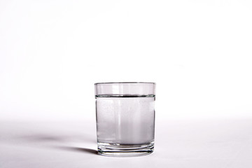 un bicchiere  trasparente pieno di acqua. vicino una bottiglia di acqua minerale. composizione con bottiglie di acqua minerale