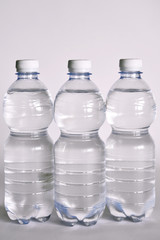 un bicchiere  trasparente pieno di acqua. vicino una bottiglia di acqua minerale. composizione con bottiglie di acqua minerale