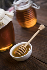 Honey in jar with honey dipper on wooden background 