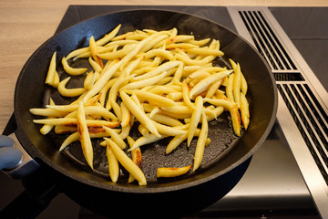 Schupfnudeln braten in Bratpfanne auf Indukstionskochfeld und Kochfeldabzug