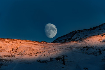 chairlift in the alps with alpenglow and rising moon