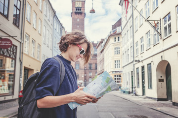 Happy young woman traveler with map in hand on the background of a European city
