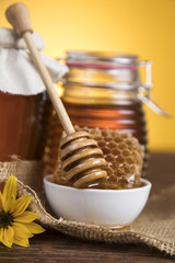 Honey in jar with honey dipper on wooden background 