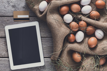 Fototapeta na wymiar Fresh chicken eggs on sack and tablet, internet order concept