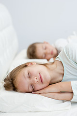 Brother and sister are sleeping in bed