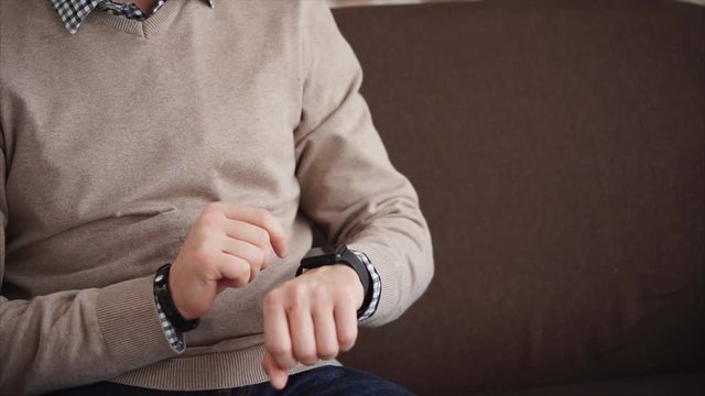 Close up shot of the men's hands, who touches the smart watch by fingers and checks incoming alerts, then he watches how long, the gadget shows incoming messages on the phone