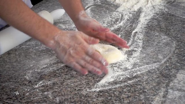 chef puts and kneads raw dough, slow motion