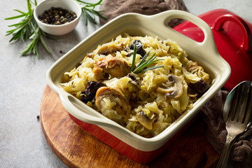 Duck stew with cabbage, prunes, mushrooms and spices on a gray stone or slate background.