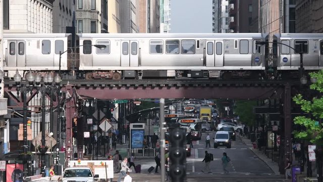 4K Chicago L Train Crosses Over Busy Street with traffic flowing in every direction around it